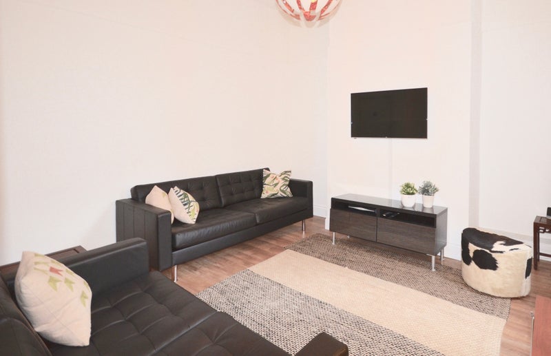 Shared lounge with two leather sofas and wall-mounted TV